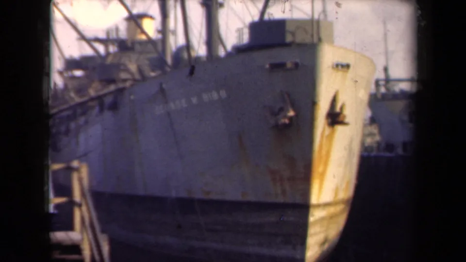 Dockside 8mm frame of the George W. Gibbs bow in the Netherlands, with visible hull lettering and a gangway or railing nearby.