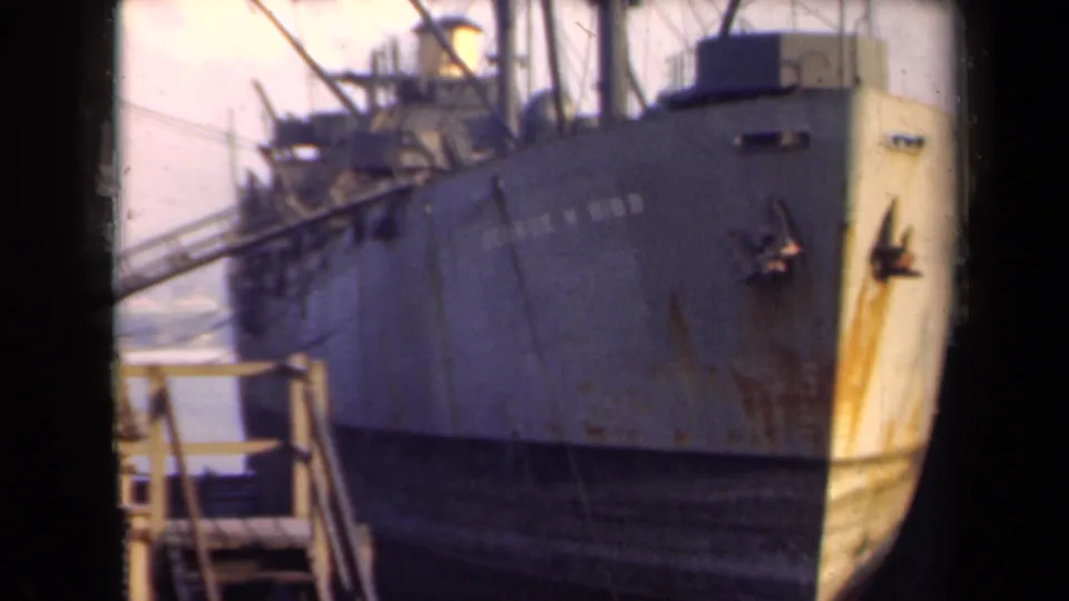 1946 Netherlands 8mm frame showing a large docked vessel with a worn bow, hull staining, rigging, and dock structures.