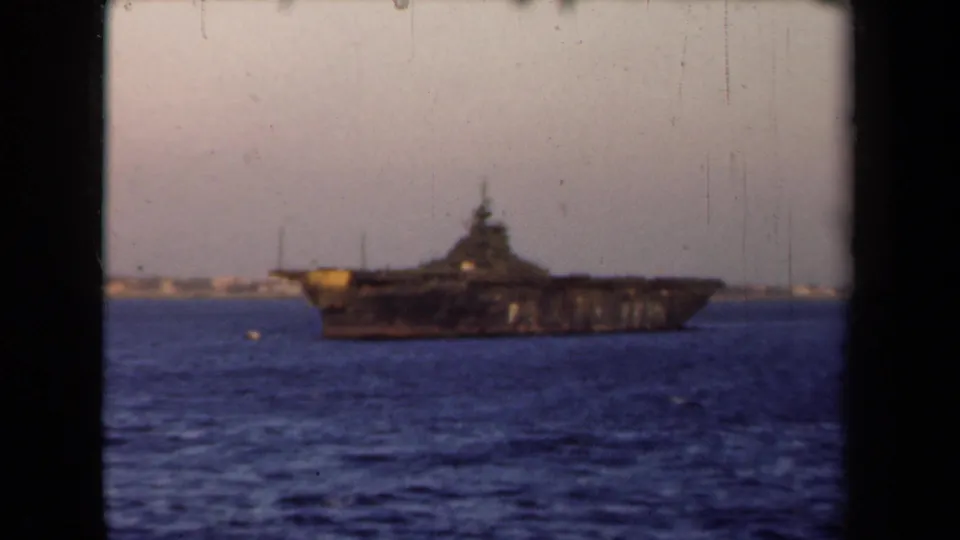 1946 Netherlands 8mm frame showing a large dark naval ship offshore, seen through black film gate edges.
