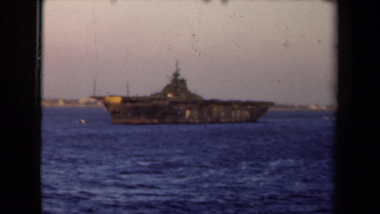 1946 Netherlands home-movie frame of a dark naval vessel on calm water beneath a pale sky.