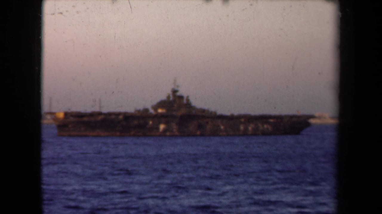 Large naval vessel on blue harbor water with a dark 8mm frame border.