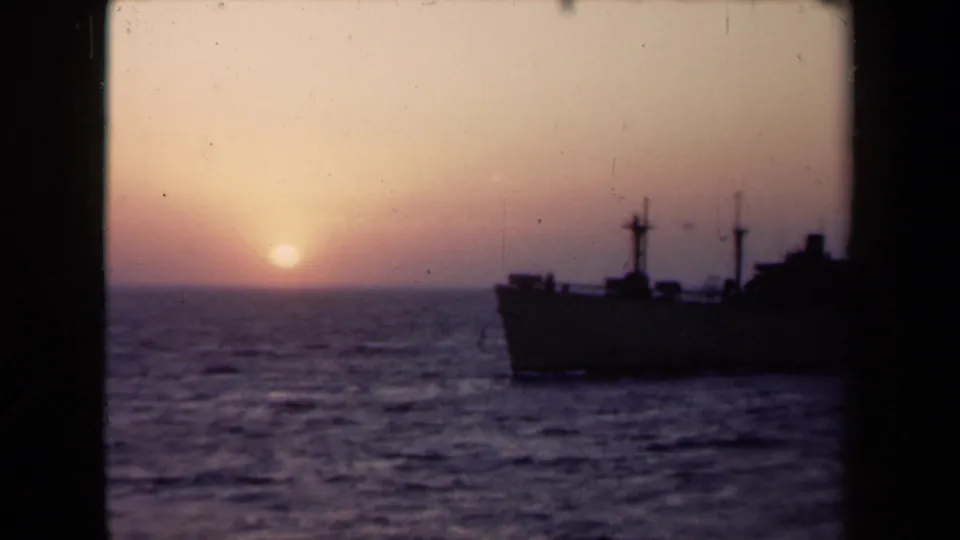 A dark vessel silhouette sits on the water as the sun drops near the horizon in the 1946 Netherlands maritime home-movie footage.
