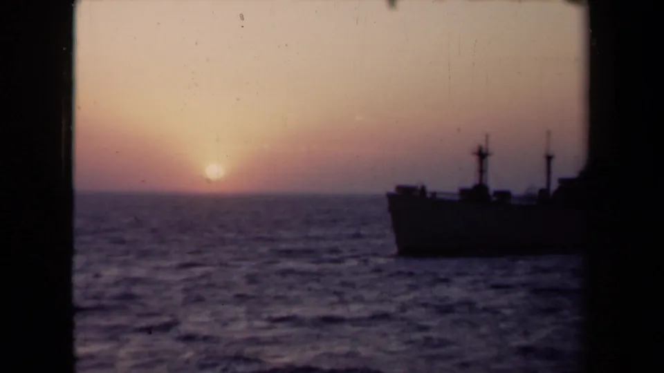1946 Netherlands 8mm frame showing a silhouetted ship partly obscured by a dark frame edge at sunset.