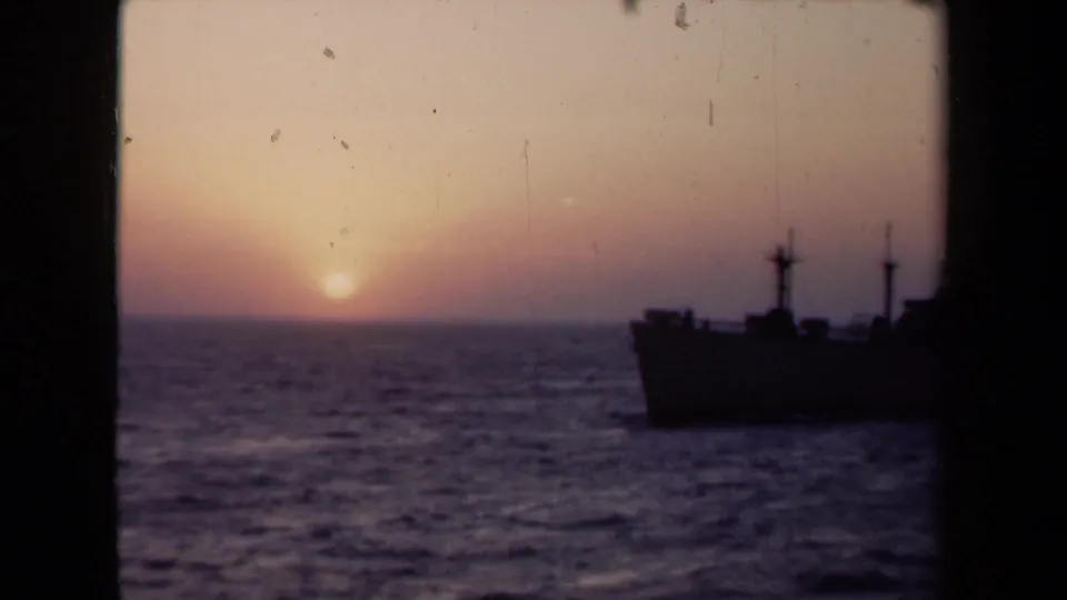 1946 Netherlands 8mm frame of a ship silhouette at right, rough water, and a low sun in a muted evening sky.