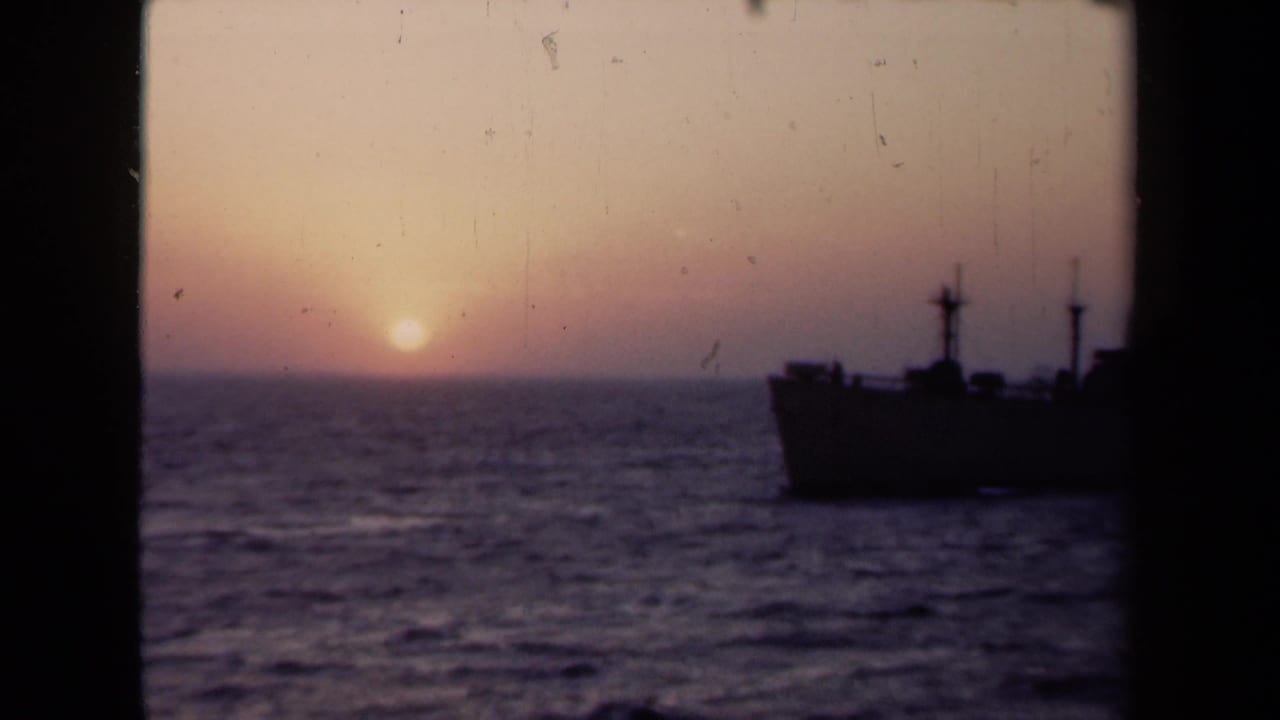 Low sun over water with a dark boat silhouette near the horizon.