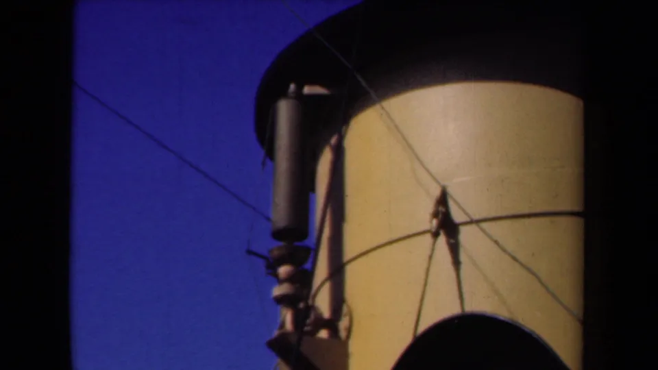 1946 Netherlands 8mm frame with a close shipboard view of a funnel, wires, and metal fitting against clear sky.