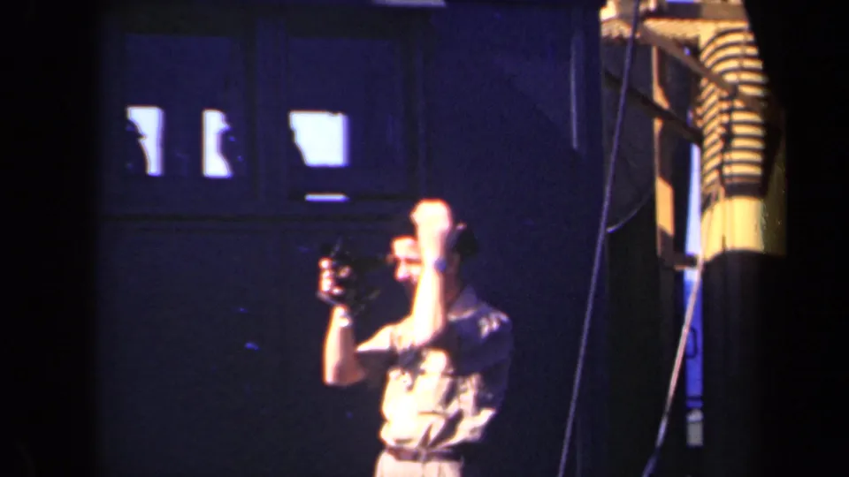 In 1946 Netherlands footage, a man appears to adjust or lift a small movie camera near dark walls and bright upper windows.