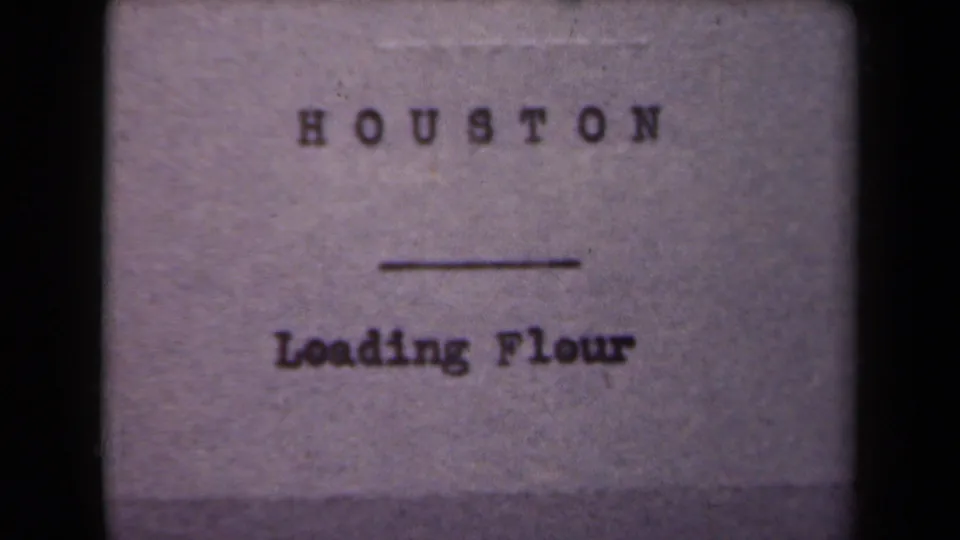 A simple typed title card identifies the scene as "HOUSTON — Loading Flour," providing an internal label for the industrial footage.