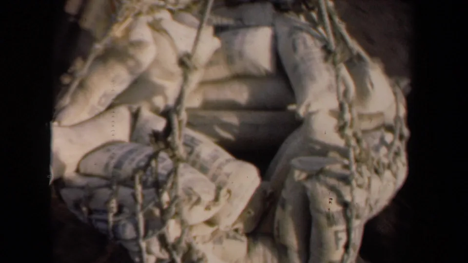 1946 Netherlands frame showing the cargo net and sacks from above, with a partial view of a worker near the right edge.