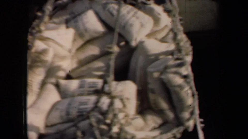 1946 8mm frame showing a loaded cargo net or sling with sacks near dark shipboard structure.