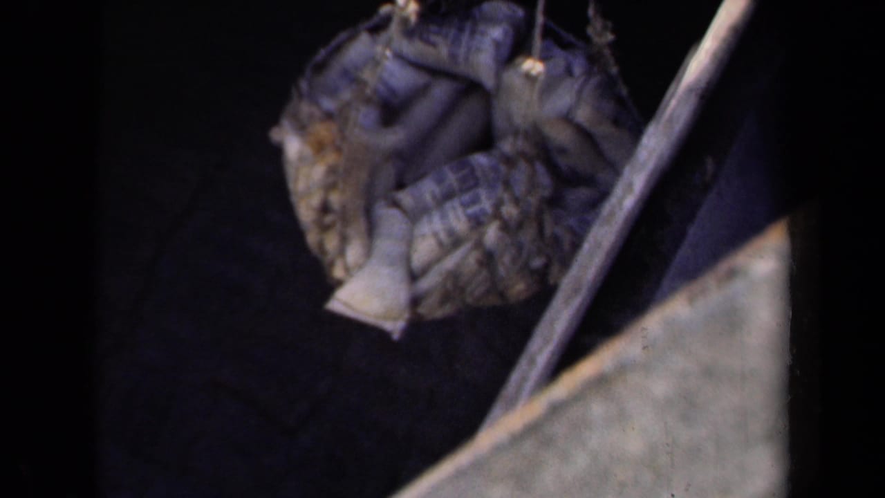 Loaded net or bundle appears near diagonal rigging and a pale ship-edge form in 1940s 8mm footage.