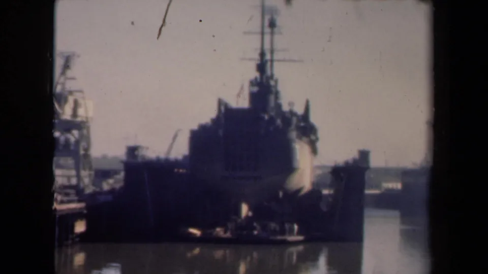 1946 Netherlands 8mm frame showing the ship closer in the port, with dock cranes, pier edges, and muted home-movie color.