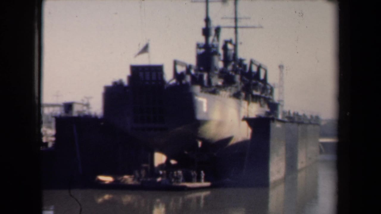 1946 Netherlands home-movie frame showing a large American military vessel docked in a harbor with small figures near the pier.