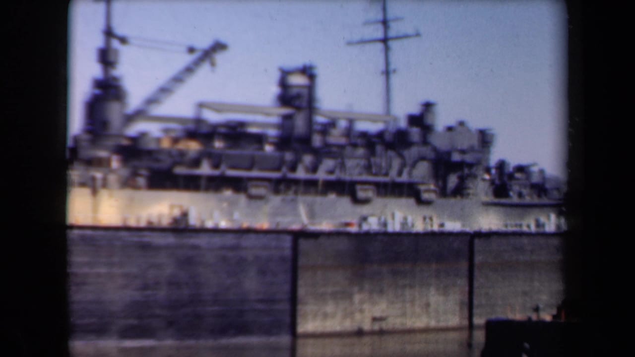 A large ship at a Netherlands port is held in a soft 8mm view, partly obscured by dark vertical film or barrier edges.