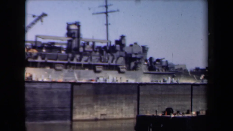 Soft 8mm footage shows the rear section of a large docked ship in the Netherlands, with deck gear and a concrete harbor wall.