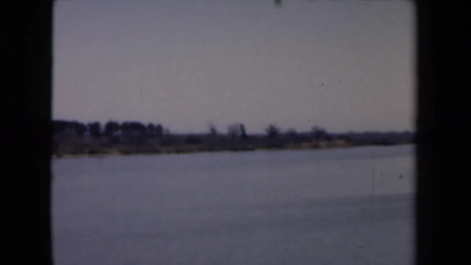 Final 1946 Netherlands river frame with open water, a distant wooded bank, and faint shoreline details.
