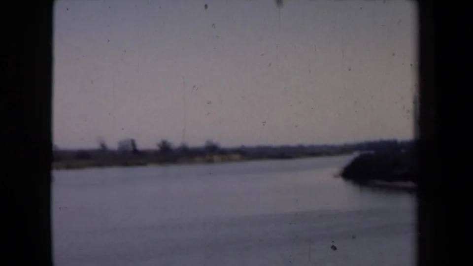 1946 Netherlands waterside view with calm water, low shore, indistinct trees or buildings, and a darker bank entering at right.