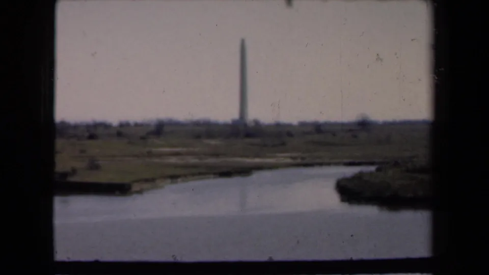 The waterside view holds on a distant monument, with soft focus, faded color, and visible 8mm film texture.