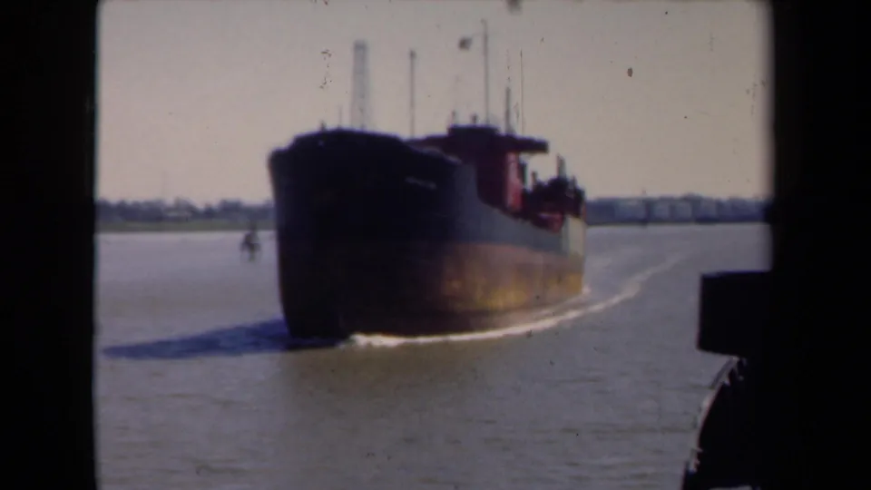 Large cargo vessel underway on a Netherlands river in 1946, filmed from a nearby boat with soft 8mm color and edge obstruction.