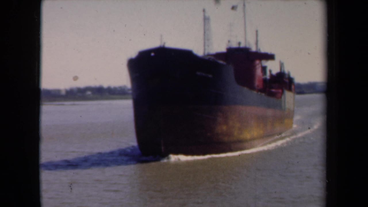 1946 Netherlands 8mm frame showing a large commercial vessel passing through a waterway, with shoreline faintly visible behind it.
