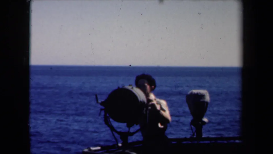 1946 Netherlands maritime frame showing a sailor near a deck-mounted searchlight, now mostly silhouetted against the ocean horizon.