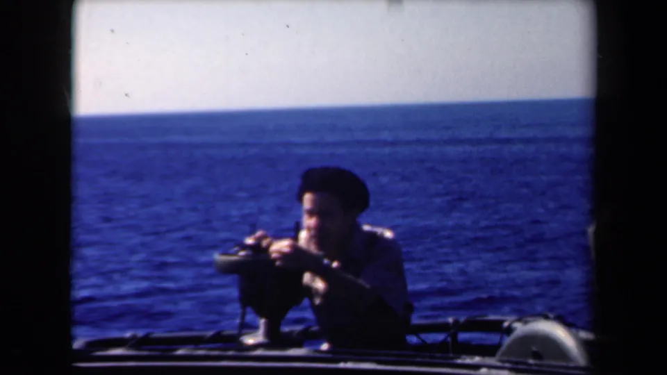 Sailor aboard the George M. Bibb appears to operate or adjust a mounted gun at sea in 1946 footage.