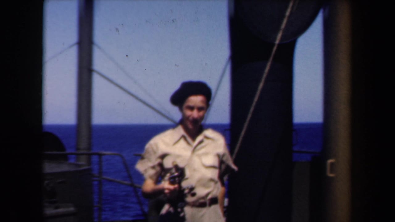 1946 Netherlands frame of a smiling sailor in khaki uniform and dark beret holding a camera beside ship railings.