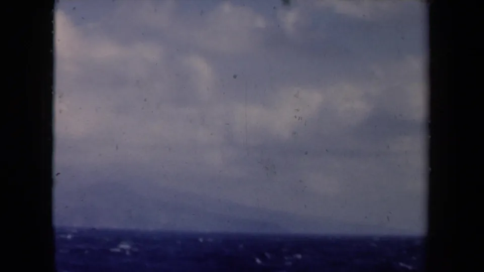 1946 Netherlands home-movie frame showing open water, cloudy sky, and distant low land from a vessel.