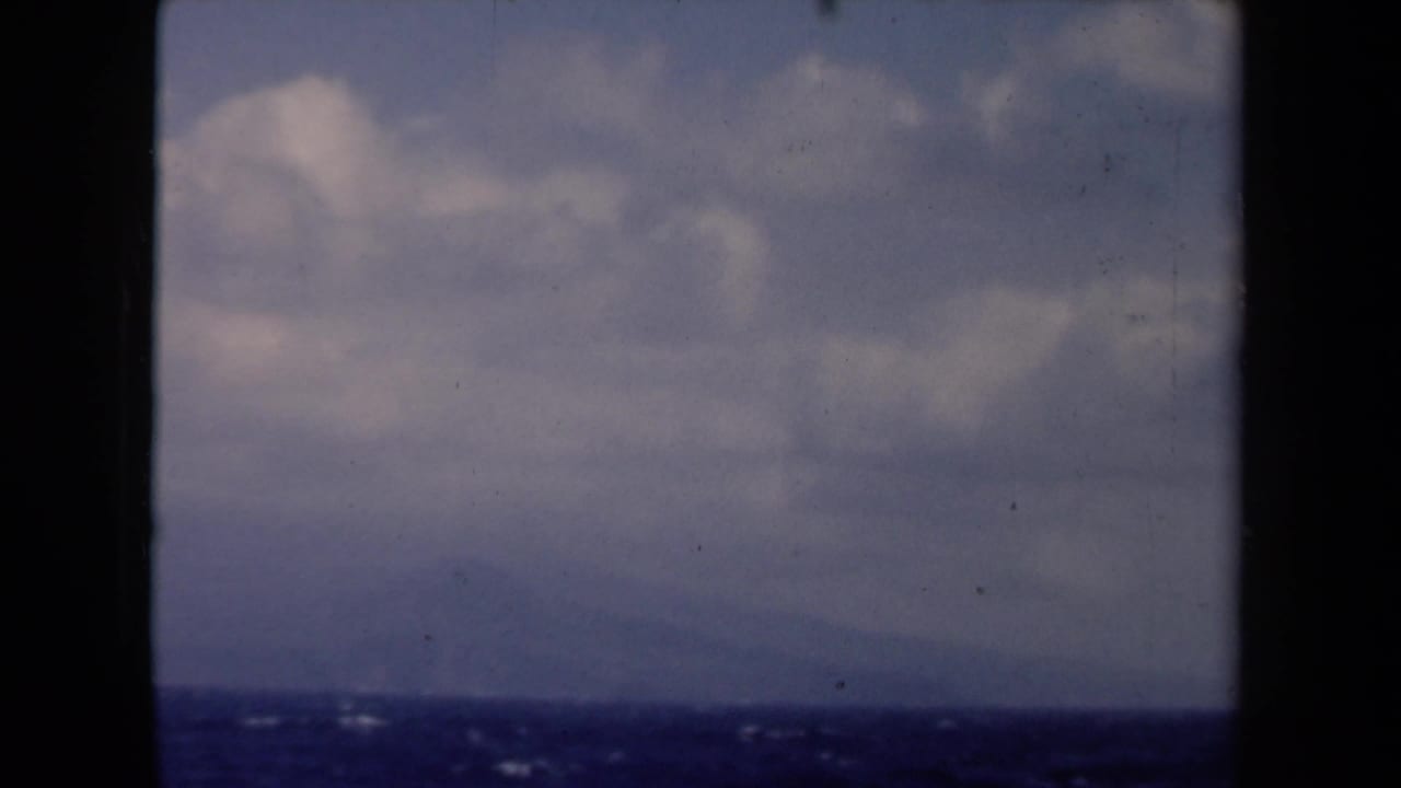 1946 Netherlands 8mm frame showing open blue water, a low distant horizon, and soft clouds within dark film-gate borders.