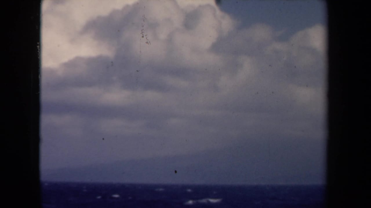 1946 Netherlands 8mm frame looking through dark borders toward a blue-gray ocean and layered overcast sky.