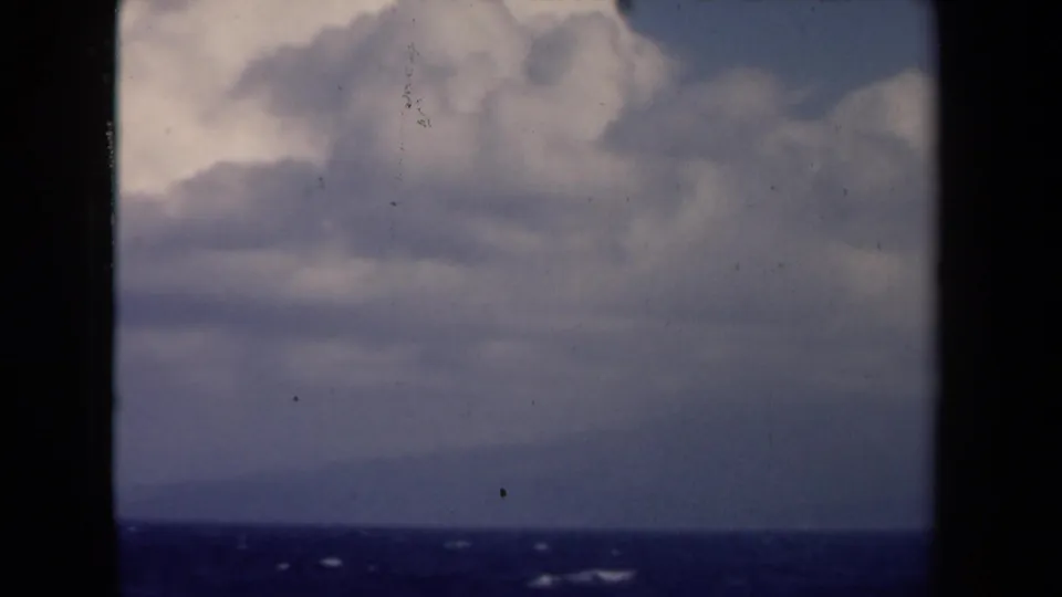 1946 Netherlands 8mm frame looking through dark borders toward a blue-gray ocean and layered overcast sky.