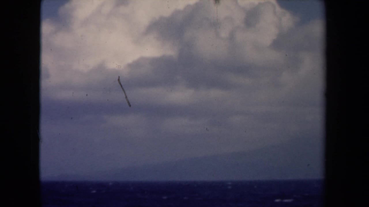1946 Netherlands maritime view with blue water, faint horizon, heavy cloud cover, and visible 8mm film marks.