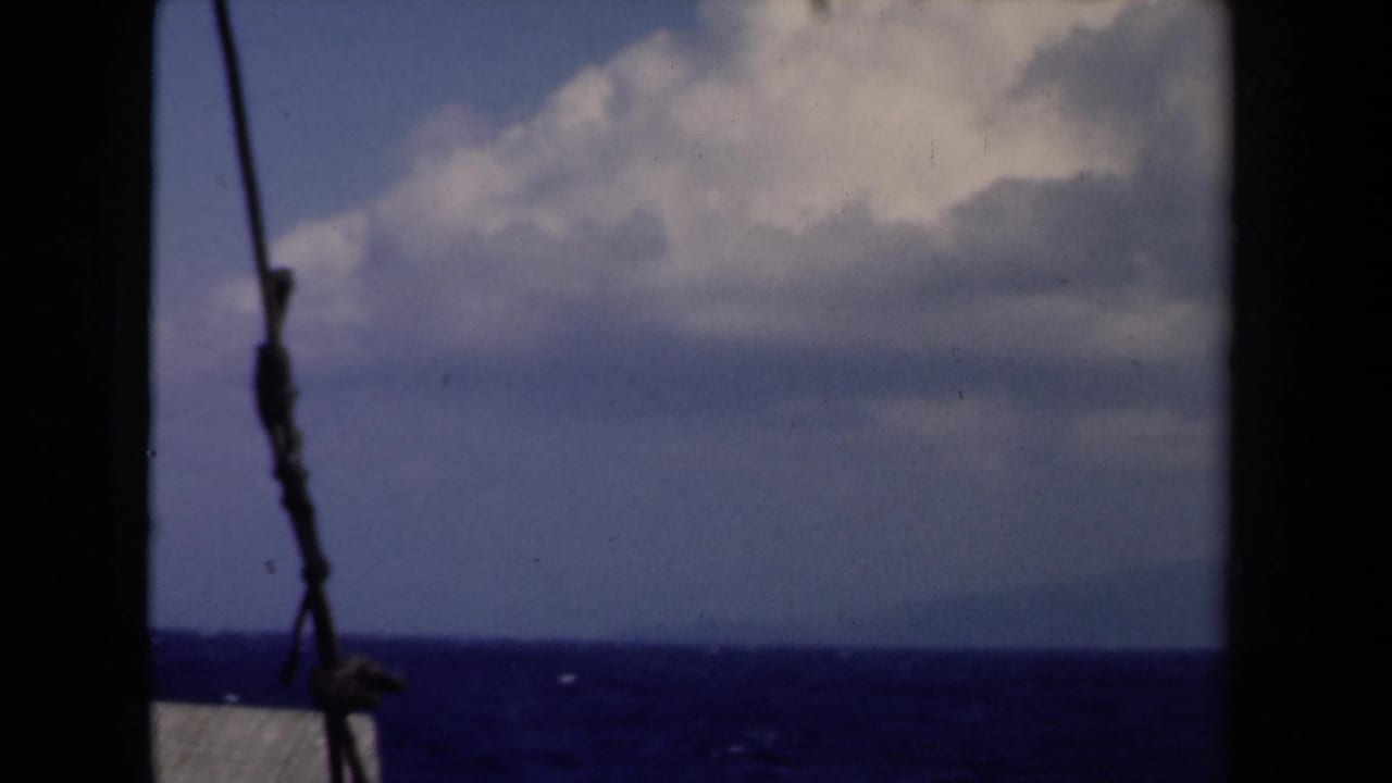 1946 Netherlands 8mm home-movie view from a boat, showing ocean horizon, cloudy sky, dark structure, and a rope or wire.