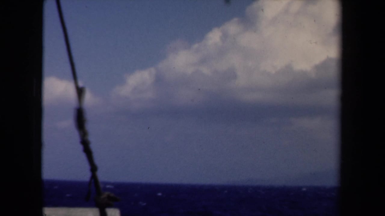 1946 Netherlands boat view with deep blue water, cloudy sky, dark ship framing, and a rope or wire in the foreground.