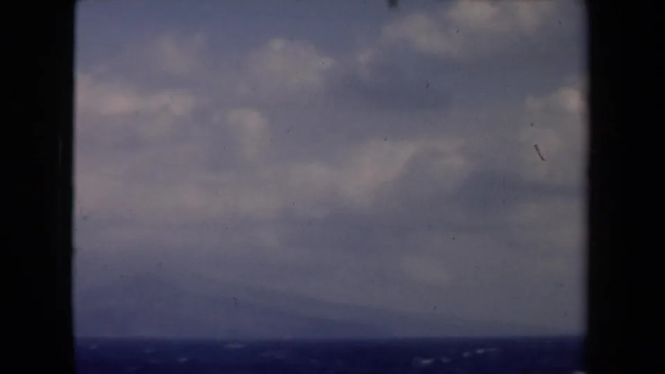 1946 Netherlands home-movie still of ocean and layered clouds through a dark boat opening, with no people visible.