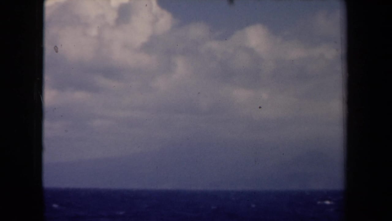 Dark window frame over blue ocean and cloudy sky with a low horizon.