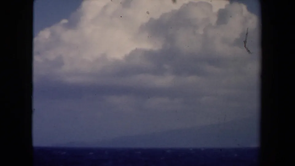 8mm maritime view from the Netherlands, showing cloud layers over the sea with a dark ship window edge.