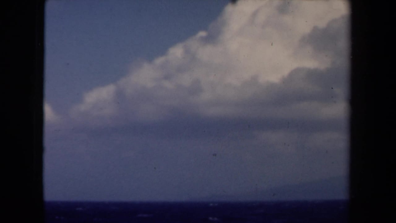 1946 Netherlands 8mm view of bright clouds over a dark sea horizon, with faint land or island shapes in the distance.