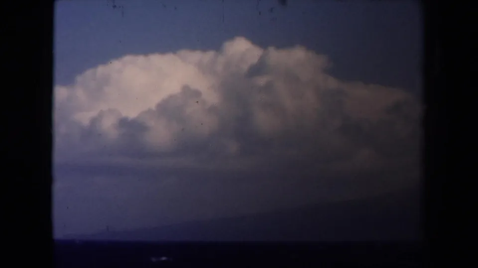 1946 Netherlands 8mm sea view with whitecaps, a faint distant island or shoreline, and soft clouds under a darkened frame edge.