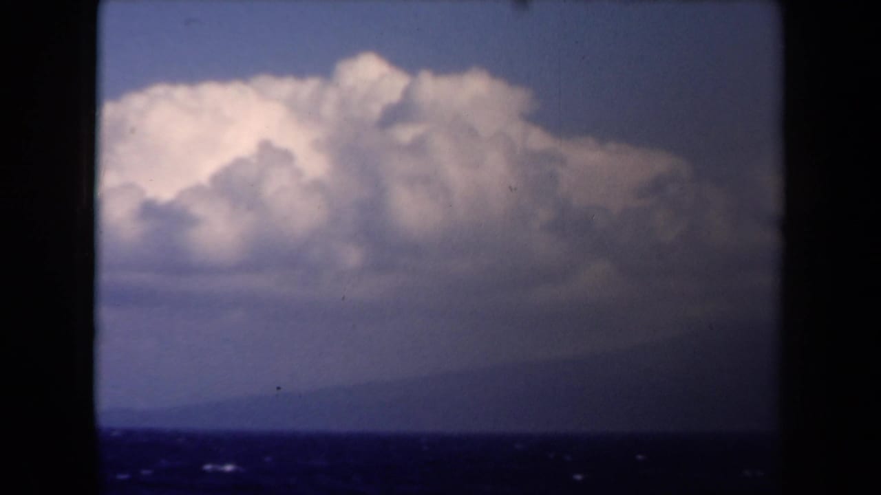 1946 Netherlands 8mm frame showing dark film borders around open sea, a hazy horizon, and billowing clouds.