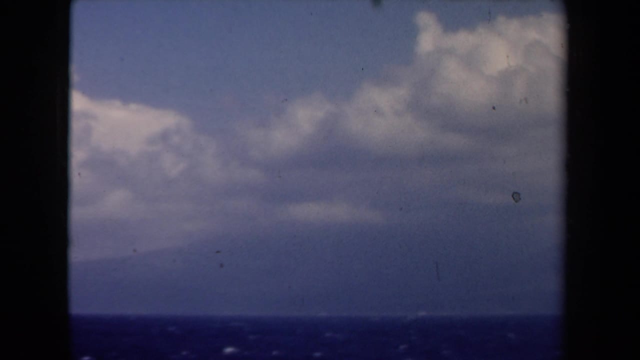 1946 Netherlands 8mm travel view of sea, distant haze, and large clouds through dark vertical and horizontal frame bars.