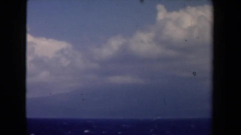 1946 Netherlands 8mm travel view of sea, distant haze, and large clouds through dark vertical and horizontal frame bars.