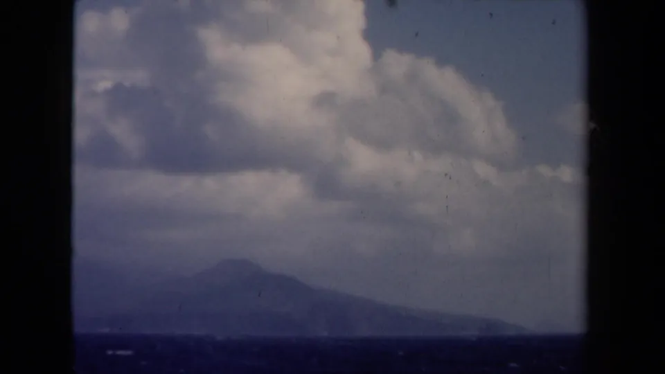 1946 Netherlands 8mm seascape showing a muted distant silhouette below a broad cloud bank and dark frame edges.