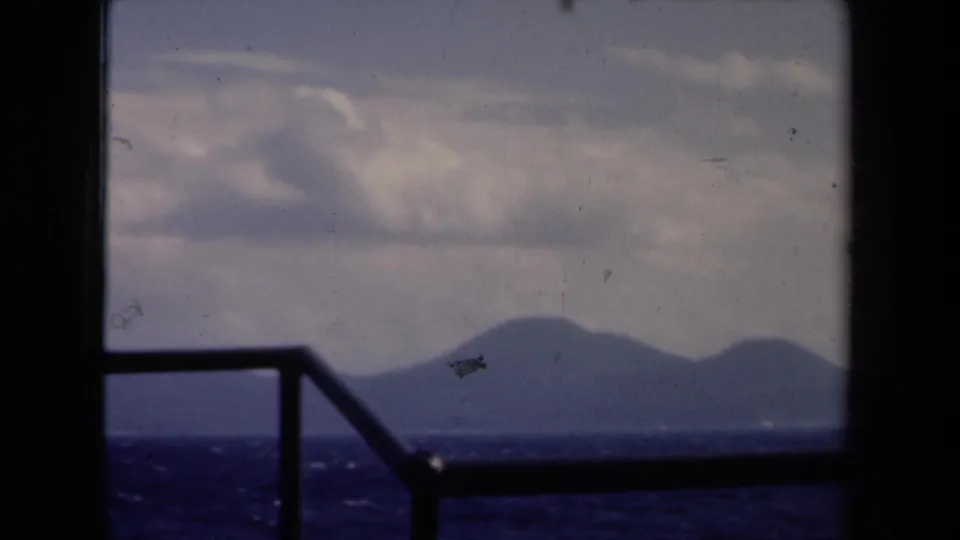 1946 Netherlands 8mm frame showing choppy water and distant land through a dark boat window frame.