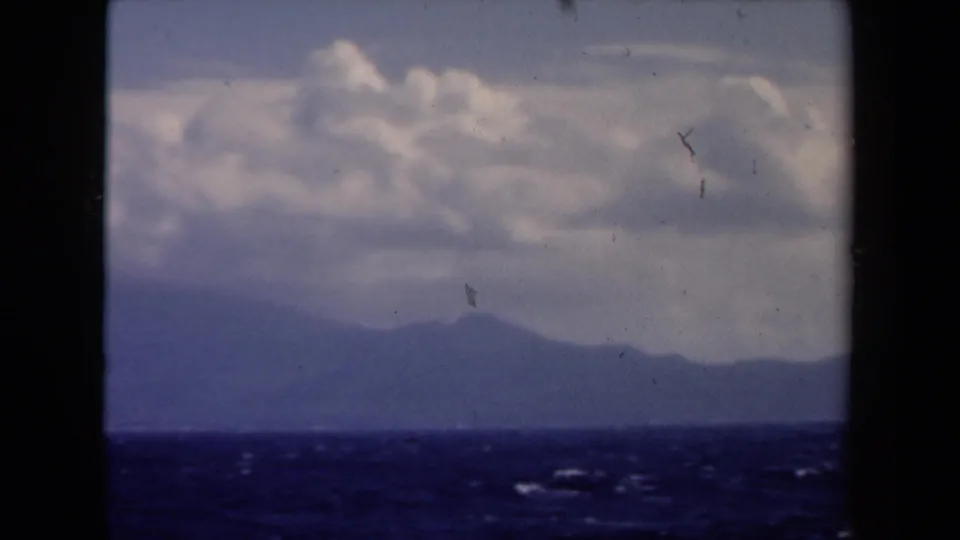 1946 Netherlands 8mm frame showing rough water, hazy distant land, and cloud cover from a boat.