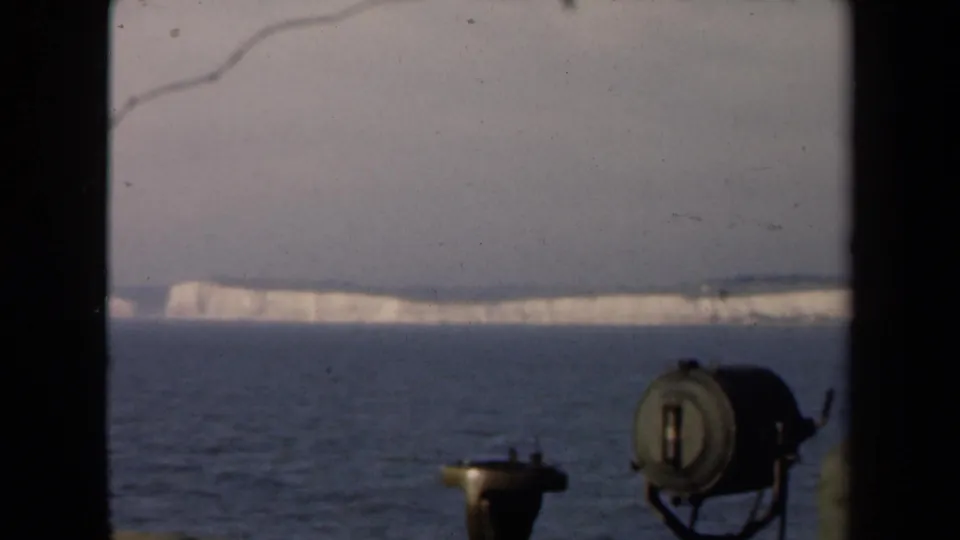 Shipboard 8mm view of the White Cliffs of Dover across the water, with equipment and frame edges visible.
