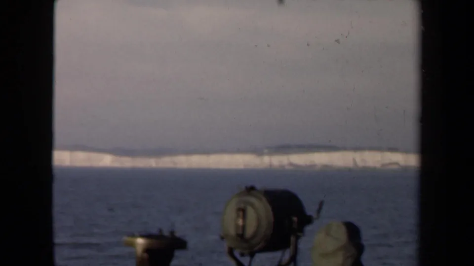 1946 Netherlands 8mm view across calm water toward a pale snow-covered shoreline, with dark framing and boat-like equipment in front.