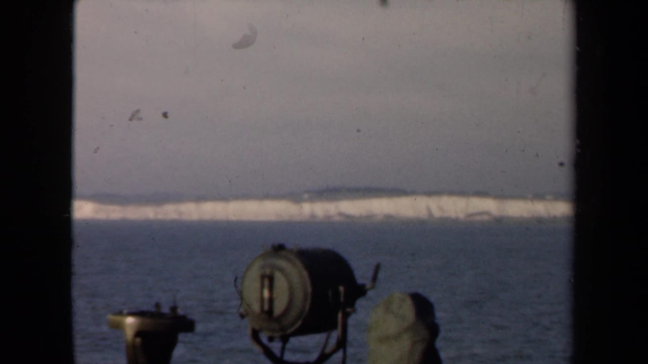 Distant snowy land across water, with a cylindrical object and dark framing in the foreground.