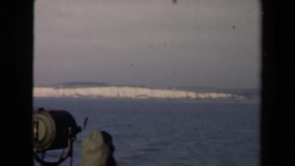 Final 1946 Netherlands 8mm frame showing calm water, a low snow-covered shoreline, gray sky, and foreground boat or dock equipment.