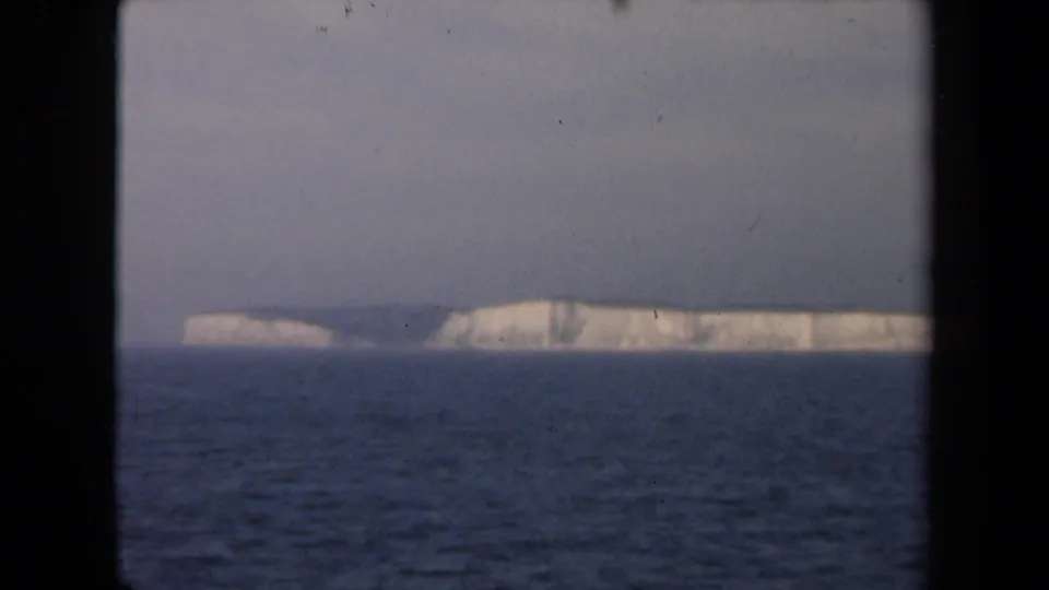 1946 Netherlands coastal view with white cliffs beyond dark water, partially divided by black film or window framing.